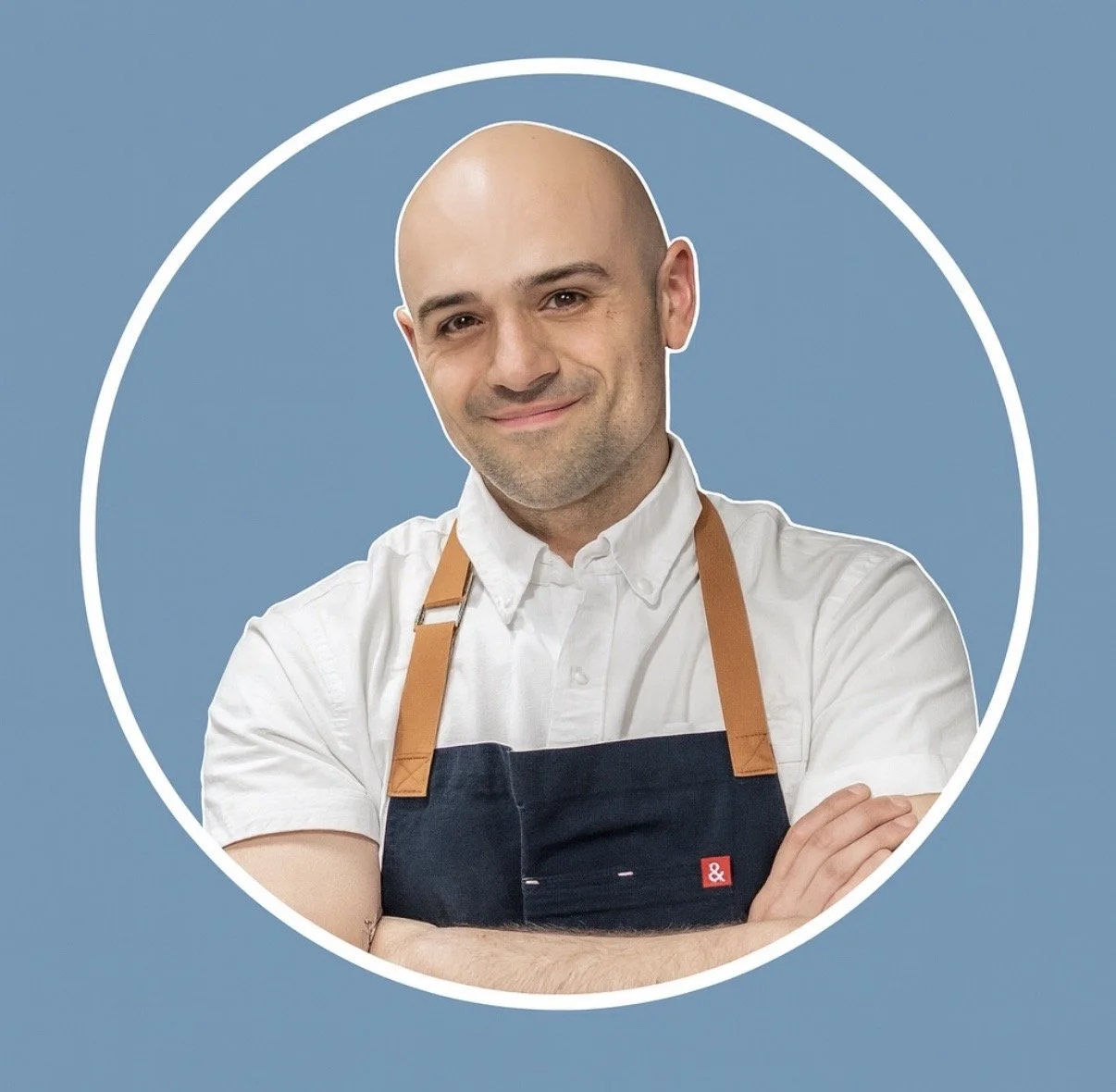 Chef Matthew, founder of Pinky's Ice Cream, smiling with arms crossed in front of a blue backdrop